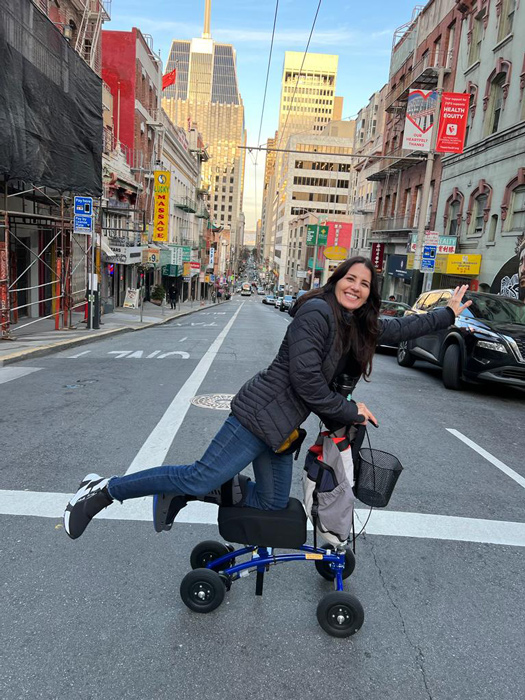 lady crossing the city street with all terrain knee scooter
