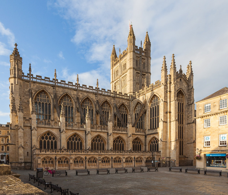 The grand facade of Bath Abbey on a clear day, showcasing its intricate Gothic architecture and towering spires.
