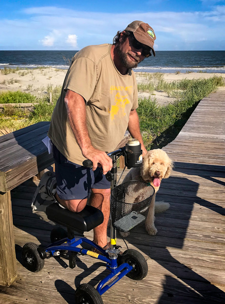 a man on his dog pose on the boardwalk, beach in the background