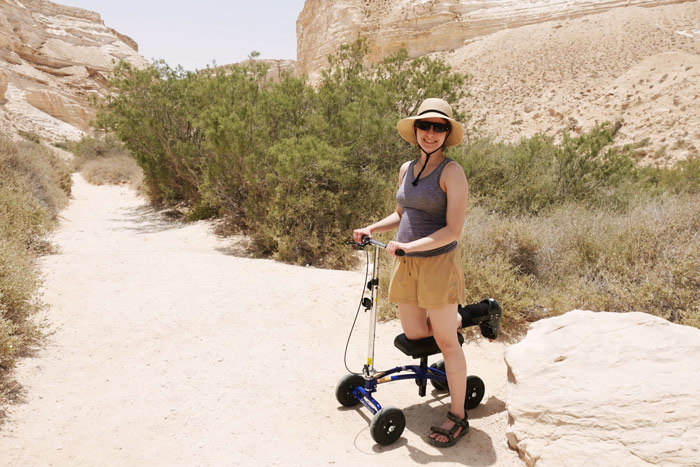 woman on a knee scooter in cobblestone terrain