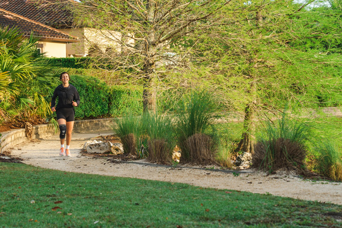 a young woman walking in a beautiful outdoor walk, she wears a knee compression sleeve