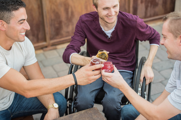 person in wheelchair drinking beer with friends