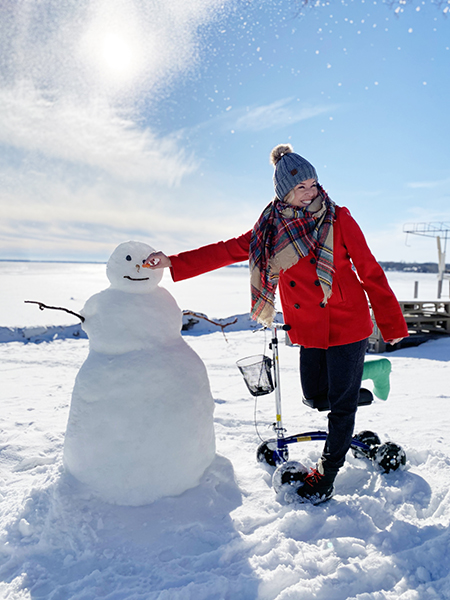 woman on a knee scooter building a snowman