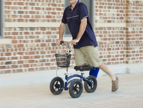 man using knee rover outside a building
