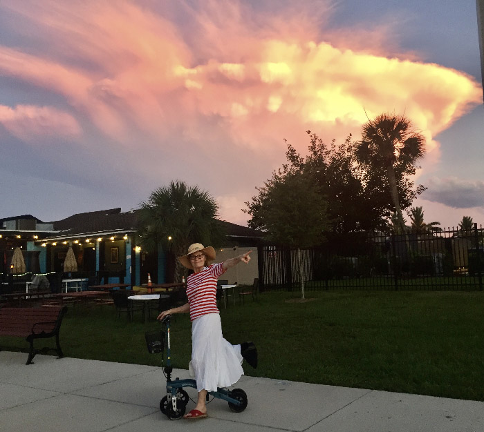 lady on a knee scooter outside a neighborhood against the sunset