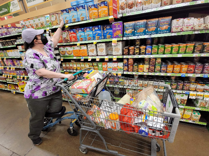 woman picking item from a grocery store shelf 