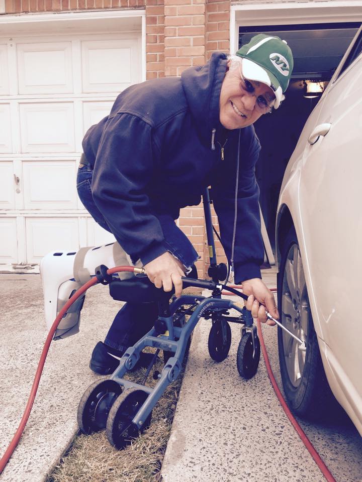 man on a knee scooter bending down and putting air on car tires