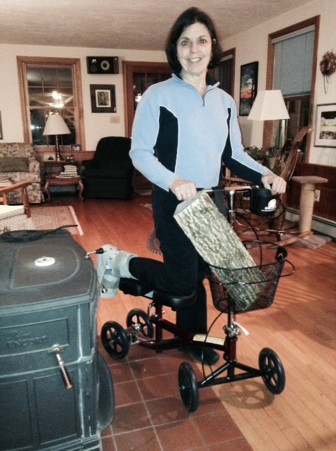 woman on a knee walker in the living room with a log on the knee scooter basket