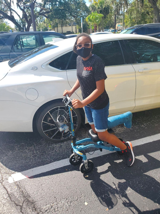 lady using knee scooter in parking lot