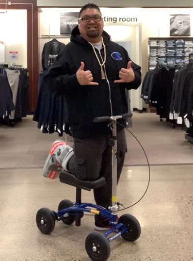 man shopping on a knee scooter