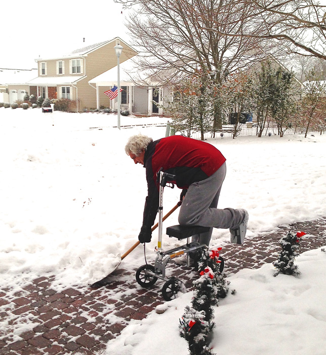 man on a knee scooter shoveling snow