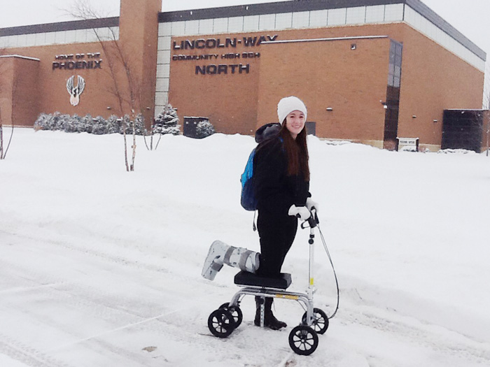 student on a knee scooter posing outside in the snow