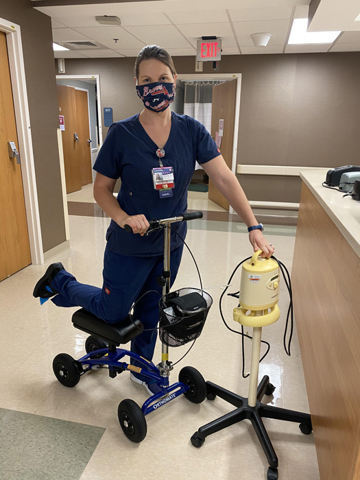 nurse using a knee scooter inside hospital
