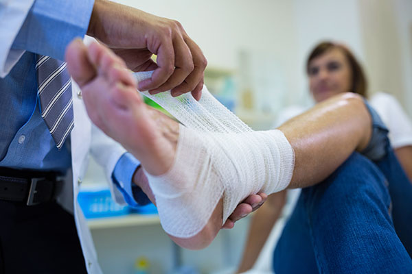 doctor putting bandage on patients foot