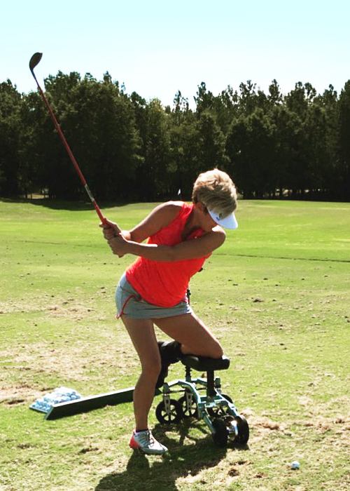 lady playing gold while supporting herself on a knee scooter