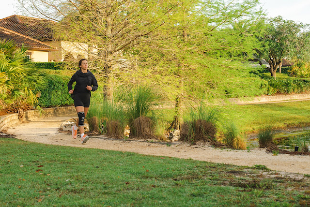 woman running outdoors with a knee compression sleeve