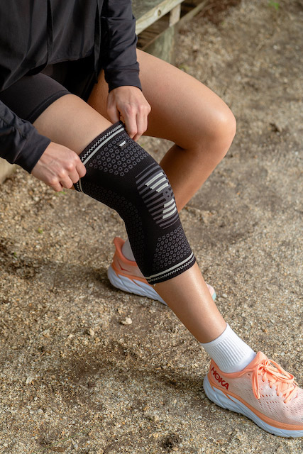 woman putting on compression sleeve on her knee