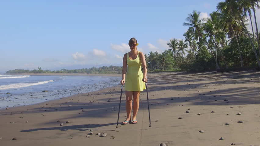 woman on beach with crutches