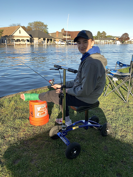 kid fishing sitting on a knee scooter