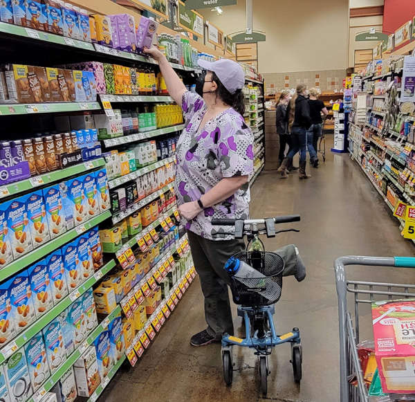 lady shopping for groceries with her knee scooter